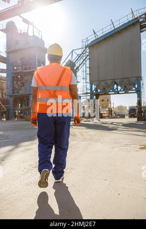 Junger Arbeiter, der in Sicherheitsausrüstung in der Fabrik gekleidet ist Stockfoto