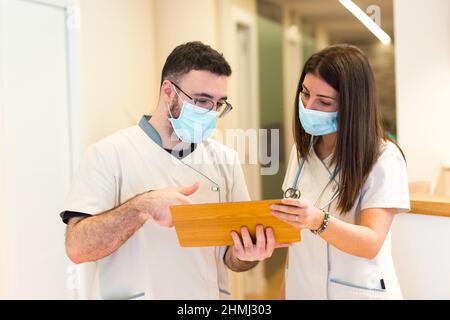 Ärztin und Krankenschwester sprechen und teilen Informationen an der Rezeption des Gesundheitszentrums. Stockfoto