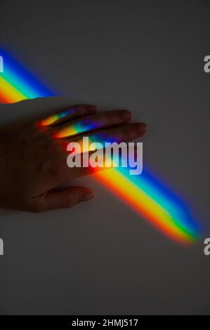 Regenbogenstrahl auf der Hand einer Frau. Stockfoto