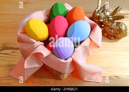 Abbildung eines Korbes mit bunten Ostereiern mit zwei kleinen Hasen im Hintergrund Stockfoto