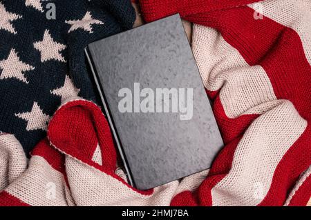 Altes Buch mit leerem Einband, eingewickelt in eine Wollflagge der Vereinigten Staaten von Amerika Stockfoto