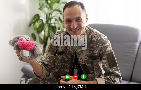 Reifer männlicher Soldat, der im Hauptquartier einen Laptop für die Kommunikation mit seiner Familie verwendet. Stockfoto
