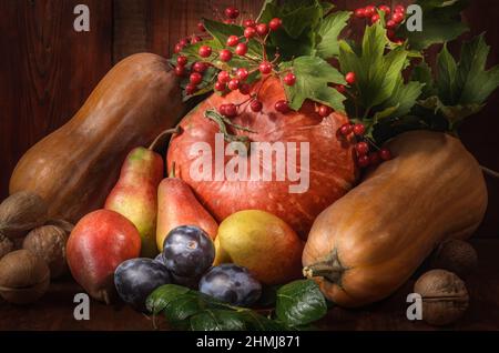 Kürbisse, Birnen, Pflaumen und andere Beeren und Früchte in großer Menge auf dunklem Holzhintergrund im rustikalen Stil Stockfoto