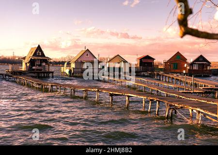 Sonnenuntergang auf schwimmenden Dorfbungalows in Bokod Ungarn mit hölzernen Steg Stockfoto