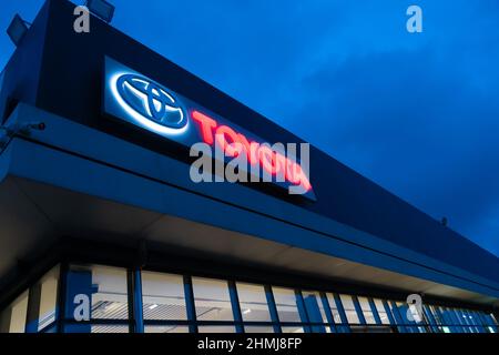 Batumi, Georgia - Januar 26 2022: Nahaufnahme des Toyota Händlerlogos, das abends auf dem Gebäude gegen den Himmel beleuchtet wird Stockfoto