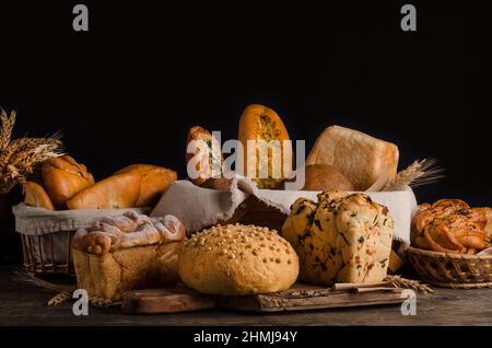 Stillleben von einer abwechslungsreichen Auswahl an Broten auf schwarzem Hintergrund, Backwaren Banner Stockfoto