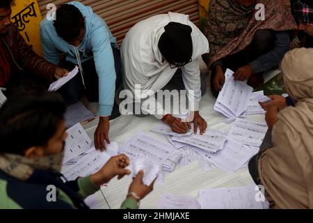 Uttar Pradesh, Neu-Delhi, Indien. 10th. Februar 2022. Die Wahlbeobachter überprüfen die Dokumente der Wähler während der ersten Phase der Parlamentswahlen im westlichen Teil von Uttar Pradesh. (Bild: © Karma Sonam Bhutia/ZUMA Press Wire) Stockfoto