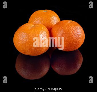 Mandarinen auf reflektierendem schwarzem Studiohintergrund Stockfoto