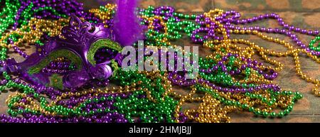 Bunte festliche mardi Gras oder Karnevalsmaske mit grünen, violetten und gelben Perlen auf rustikalem Fliesenhintergrund, selektiver Fokus, Copyspace, Banner Stockfoto