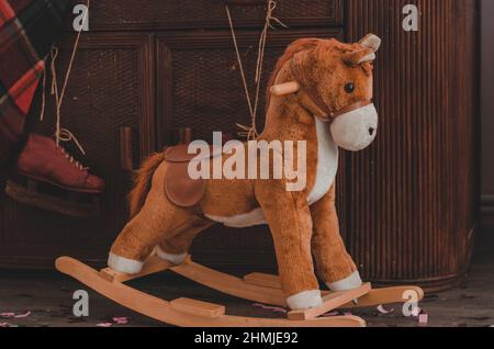 Weiches Schaukelpferd für Kinder auf dem Hintergrund einer alten Kommode Stockfoto