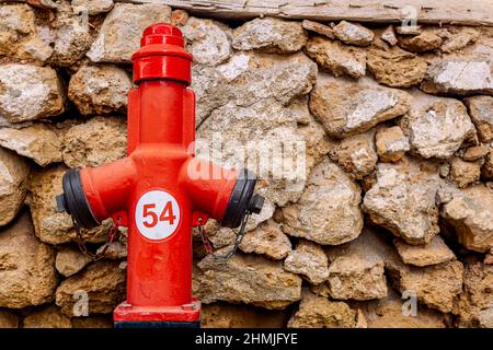 Roter Hydrant in der Nähe der alten Steinwand Stockfoto