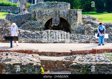 Zwei Frauen, Touristen, stehen getrennt und lesen Informationstafeln in den Ruinen der St. Augustine's Abbey in Canterbury bei strahlendem Sonnenschein. Stockfoto