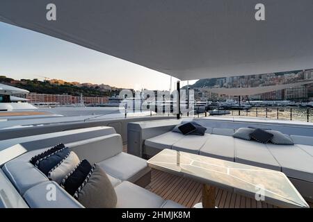 Das vordere Deck der riesigen Yacht im Hafen von Monaco bei Sonnenuntergang, der Ort für die Landung des Hubschraubers, viele Motorboote sind im Hintergrund, das Chrom Stockfoto