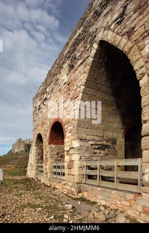 Castle Point Line Brennöfen mit Schloss Lindisfarne hinter sich, Holy Island, Northumberland, Großbritannien. Stockfoto