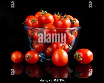 Kirschtomaten auf schwarzem reflektierendem Hintergrund Stockfoto