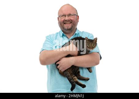 Ein kahler Mann hält eine Katze in den Armen und lächelt. Stockfoto