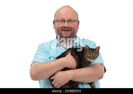 Ein kahler Mann hält eine Katze in den Armen und lächelt. Stockfoto