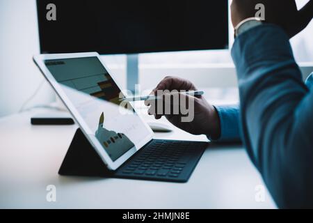 Gesichtslose intelligente männliche Unternehmer arbeiten auf Tablet mit Stift Stockfoto