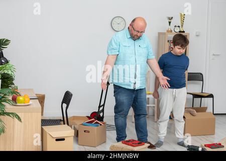 Ein Vater und ein Sohn machen sich daran, ein Bücherregal zusammenzustellen. Stockfoto