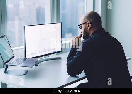 Ernsthafter Mann, der im Büro am Computer arbeitet Stockfoto
