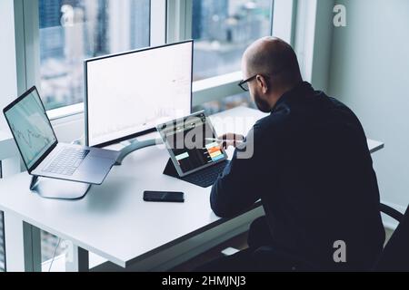 Anonymer Händler, der Daten auf Tablets und Computern im Büro analysiert Stockfoto
