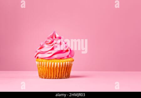 Pink Cupcake mit Buttercreme auf einem rosa Hintergrund. Stockfoto