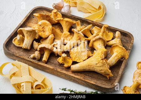 Zutaten für die Herstellung von italienischen Pasta mit Pilzen Pfifferlinge Set, auf weißem Stein Tisch Hintergrund Stockfoto