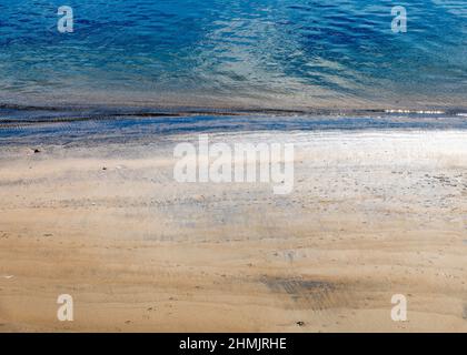 Nahaufnahme von sanften Wellen, die gegen das Ufer schlagen. Stockfoto