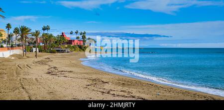 Panoramalandschaft, ruhiges Mittelmeer, Palmen am Sandstrand der spanischen Touristenstadt Benalmadena, wolkiger Himmel über dem Wasser. Bil Bil Ca. Stockfoto