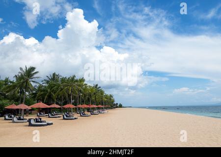 Leerer Strand mit Sonnenschirmen und Liegestühlen. Palmen. Wunderschöner Blick auf die Seenlandschaft im Sommer. Erholungsorte Insel Bali Insel, Indonesien Stockfoto