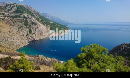 Felsiger Strand, bue transparentes Meer mit Booten Stockfoto