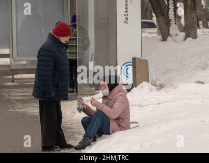 Im Winter 2022 sitzt eine Frau im Schnee Stockfoto