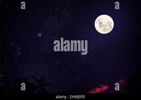 Super Vollmond vor dem Hintergrund des Sternenhimmels und atmenden Vulkans Stockfoto