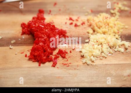 Gehackte rote Chili und Knoblauch auf ein Schneidbrett aus Holz Stockfoto