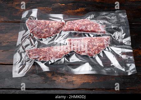 Beef Patties in einer Vakuumverpackung, auf altem dunklen Holztisch Hintergrund Stockfoto