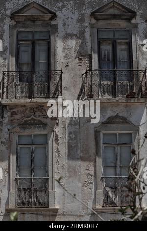 Lange, bandige Stadthäuser mit abgesplitterter Fassade, geschlossene Balkone und Balkone mit Metallgeländern. Tavira-Portugal-094 Stockfoto