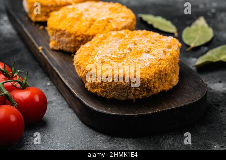 Set aus rohen Lachs-Burger-Patties auf schwarzem, dunklem Steintisch Stockfoto