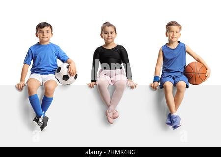 Ballerina Mädchen, Jungen mit Fußball und Basketball sitzen auf einem leeren Panel isoliert auf weißem Hintergrund Stockfoto