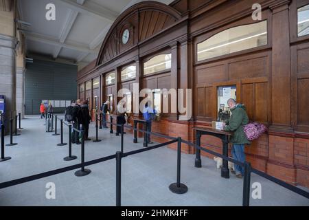 Bahnreisende stehen Schlange, um Bahntickets am Kartenbüro des Bahnhofs Manchester Victoria zu kaufen Stockfoto