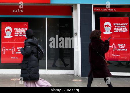 London, Großbritannien. 10th. Februar 2022. Die Frauen gehen an einem Plakat vorbei, das in einem Schaufenster zu sehen ist.Premierminister Boris Johnson hat angekündigt, dass er den Plan der Regierung für ein Leben mit Covid-19 vorstellen wird, wenn das Parlament am 21. Februar aus einer kurzen Pause zurückkehrt. Alle Covid-19-Beschränkungen müssen verschrottet werden. Kredit: SOPA Images Limited/Alamy Live Nachrichten Stockfoto