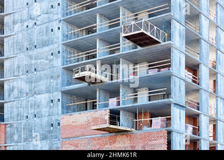 Nach und nach werden Ziegelwände und interne Trennwände auf dem Betonrahmen des im Bau befindlichen Hauses errichtet. Stockfoto