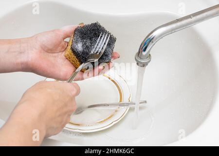 Frau wäscht Gabeln im Waschbecken mit einem Schwamm. Hochwertige Fotos Stockfoto