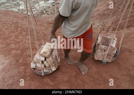 Dhaka, Bangladesch. 10th. Februar 2022. Arbeiter aus Bangladesch entladen Ziegelsteine aus einem Boot am Ufer des Flusses Buriganga, Dhaka, Bangladesch, 10. Februar 2022. Der Buriganga River ist einer der am stärksten verschmutzten und biologisch toten Flüsse der Welt. (Foto von Suvra Kanti das/Sipa USA) Quelle: SIPA USA/Alamy Live News Stockfoto