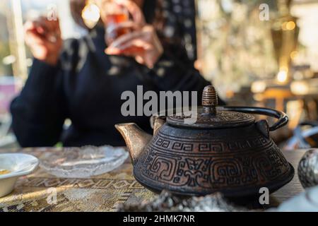 Verschwommene aserbaidschanische Frau trinkt traditionellen Tee mit Metall-Teekannen Stockfoto