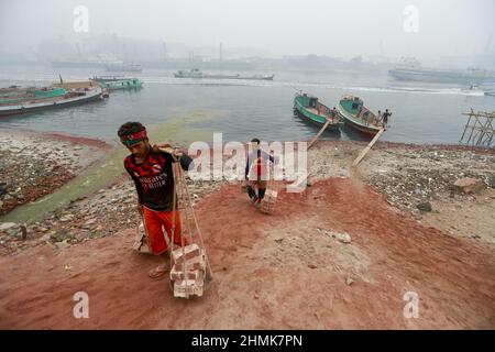 Dhaka, Bangladesch. 10th. Februar 2022. Arbeiter aus Bangladesch entladen Ziegelsteine aus einem Boot am Ufer des Flusses Buriganga, Dhaka, Bangladesch, 10. Februar 2022. Der Buriganga River ist einer der am stärksten verschmutzten und biologisch toten Flüsse der Welt. (Foto von Suvra Kanti das/Sipa USA) Quelle: SIPA USA/Alamy Live News Stockfoto