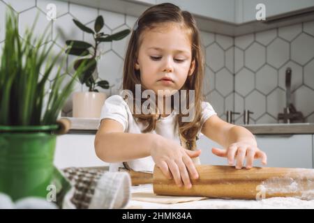 Portrait von kleinen ernsthaften Mädchen, helfen, lernen, rollenden Teig, Form ostern Cookies. Mehl-Biskuit Formen. Vorbereiten des Haltestrombolzens Flo Stockfoto