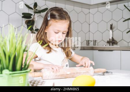 Portrait von kleinen ernsthaften Mädchen, helfen, lernen, rollenden Teig, Form ostern Cookies. Mehl-Biskuit Formen. Vorbereiten des Haltestift. Ye Stockfoto