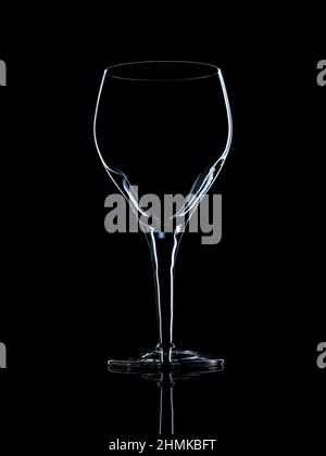 Leeres Kristall-Rotweinglas auf schwarzer reflektierender Oberfläche mit Randlicht Stockfoto