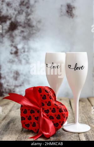 Valentinstag-Konzept. Zwei Gläser für Champagner und herzförmige Geschenkbox auf einem Holztisch. Selektiver Fokus. Stockfoto