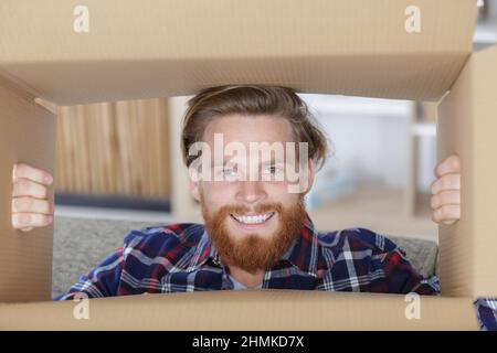 Freudiger Mann öffnet die Kiste und sieht überrascht aus Stockfoto